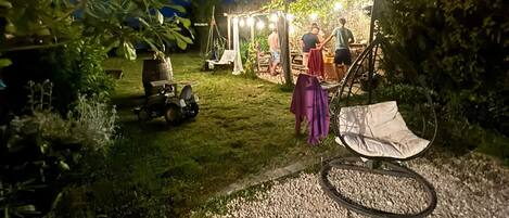 A gravel path leading to a rustic outdoor area with a hanging chair and a small table.