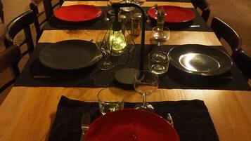 Una mesa de comedor dispuesta con platos rojos y negros, vasos y una botella.