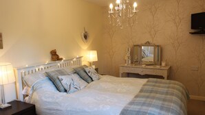 A bedroom with a bed, nightstands, a dresser, a mirror, and a chandelier.