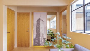 Un pasillo con puertas de madera, un espejo grande que refleja un edificio y una planta en maceta.