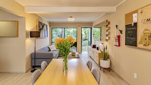 Un moderno salón con una mesa de comedor de madera, un sofá gris y un jarrón con flores.