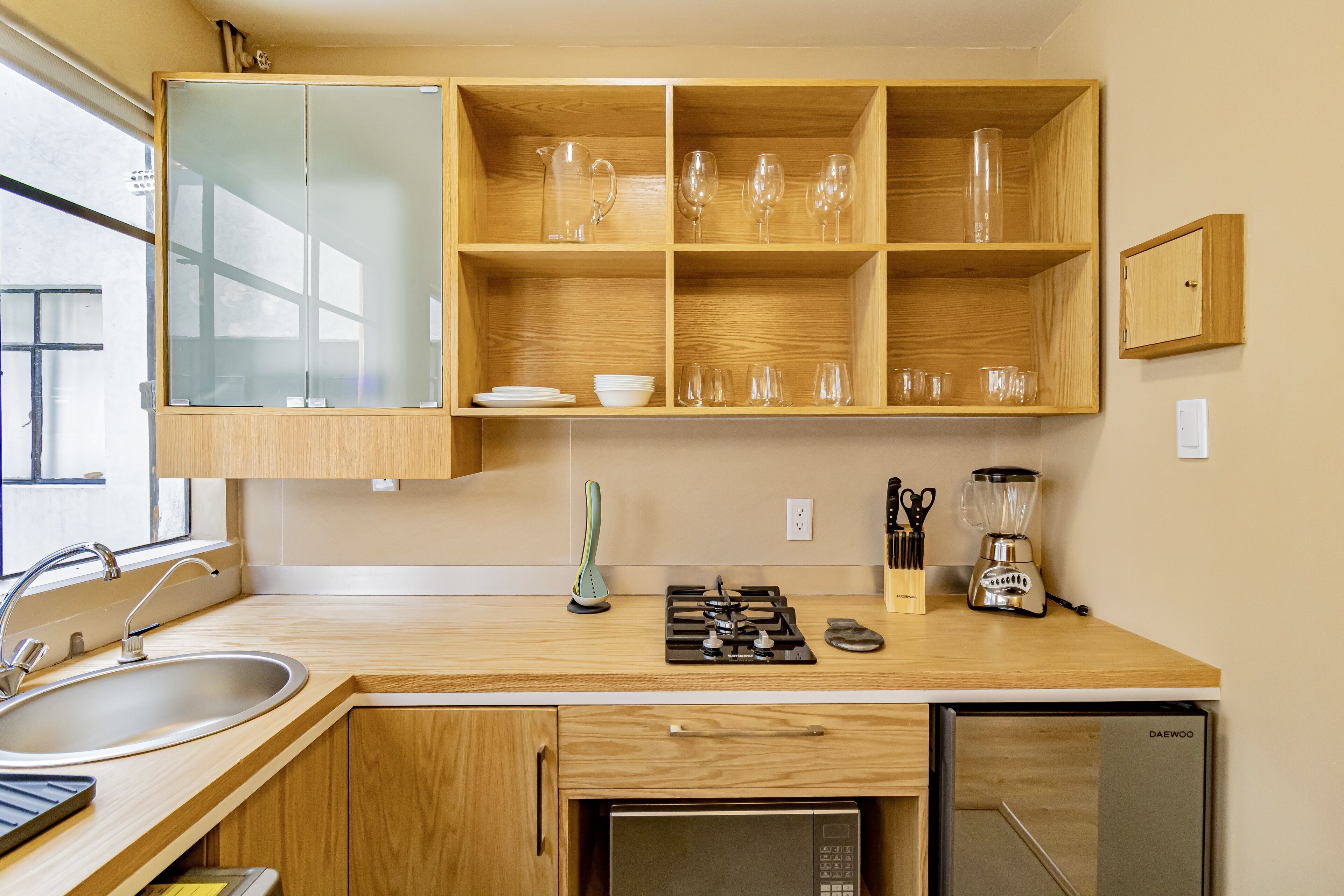 Una cocina moderna con armarios de madera, estufa integrada, pileta y refrigerador.