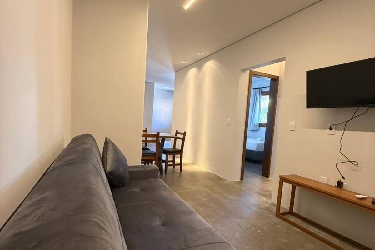 A modern living room with a grey sofa, a wooden coffee table, and a mounted TV.