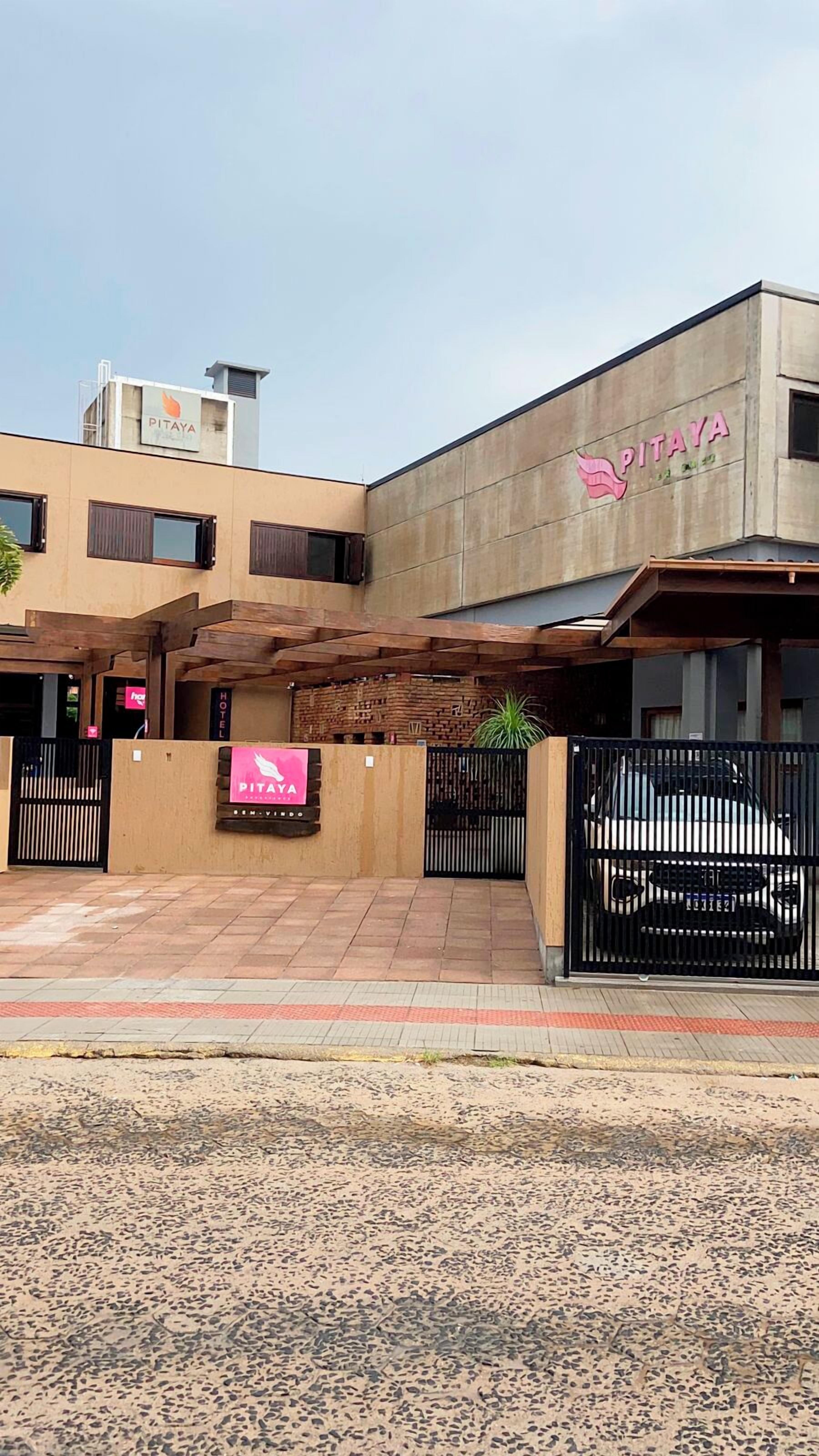 Un edificio con un letrero que dice 'PITAYA' y una entrada protegida por una reja.