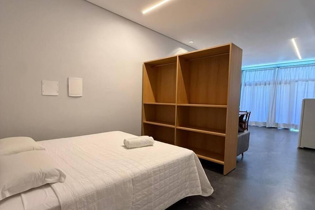 A modern bedroom with a bed, a wooden wardrobe, and a desk.
