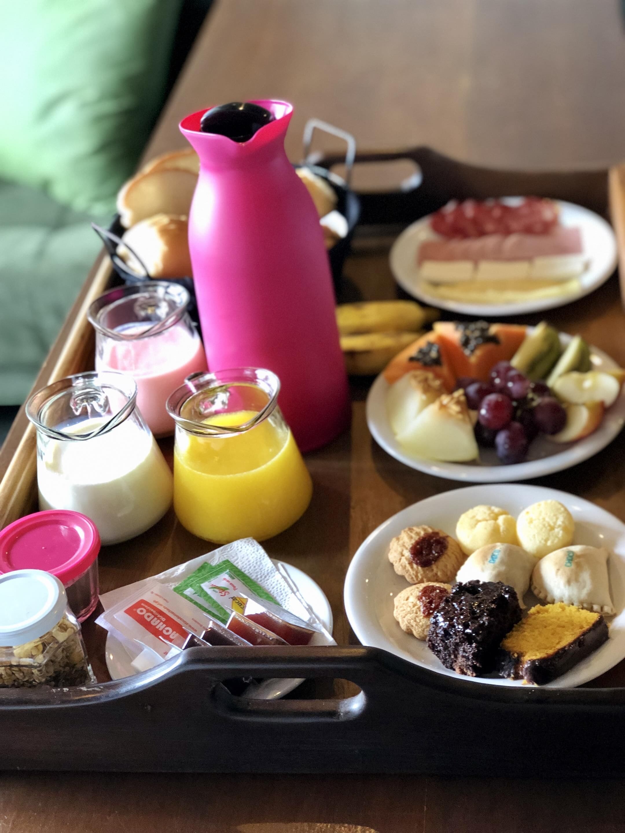 Un plateau de petit-déjeuner contenant divers aliments, une bouteille d’eau rose et deux verres de lait et de jus d’orange.