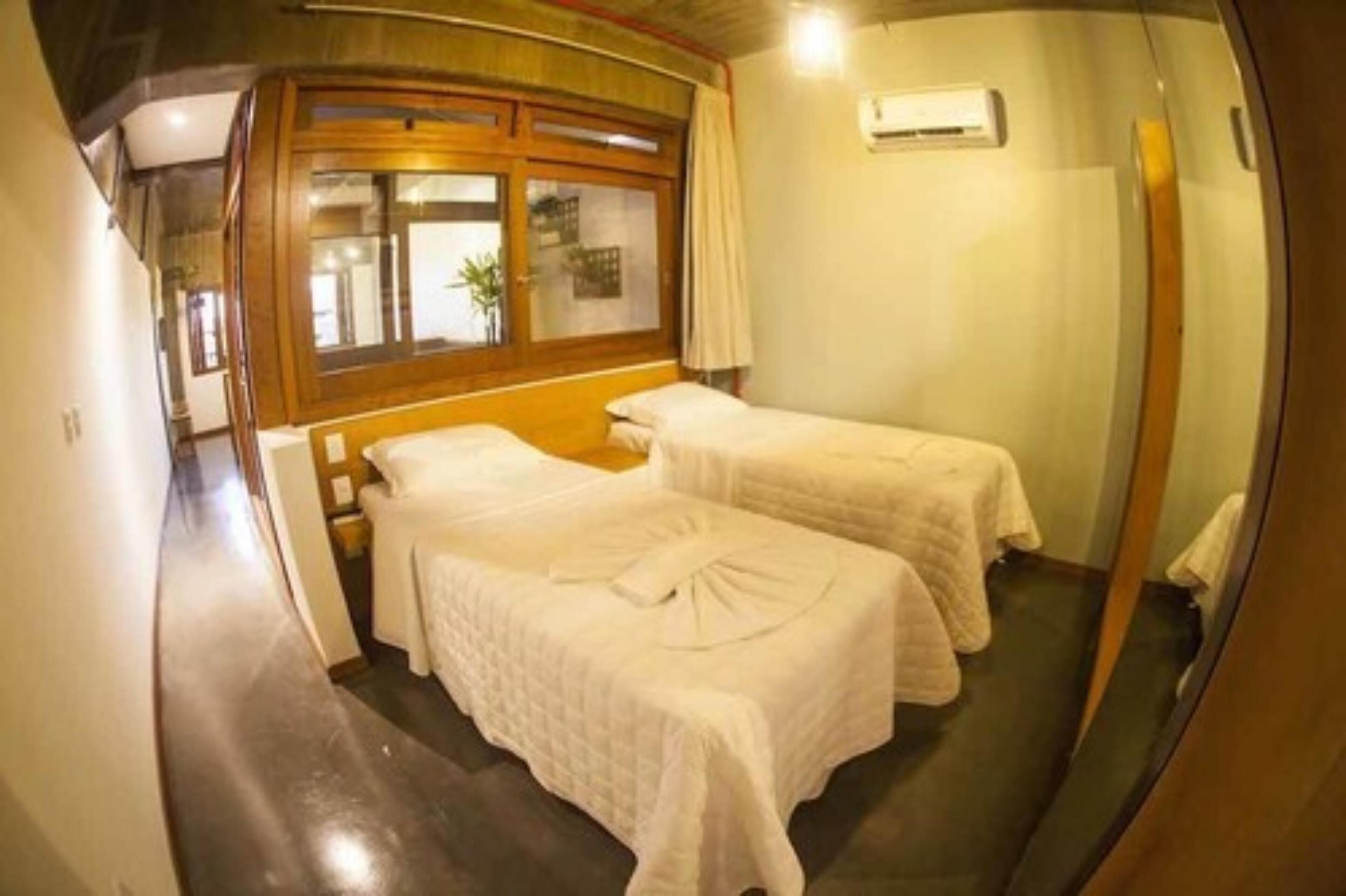 Una habitación con dos camas, ventana con vistas y cabecero de madera.