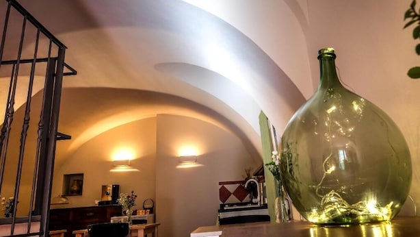 A room with a curved ceiling, a staircase, and a large green bottle on a table. - B&B U Campanin (Dolceacqua)