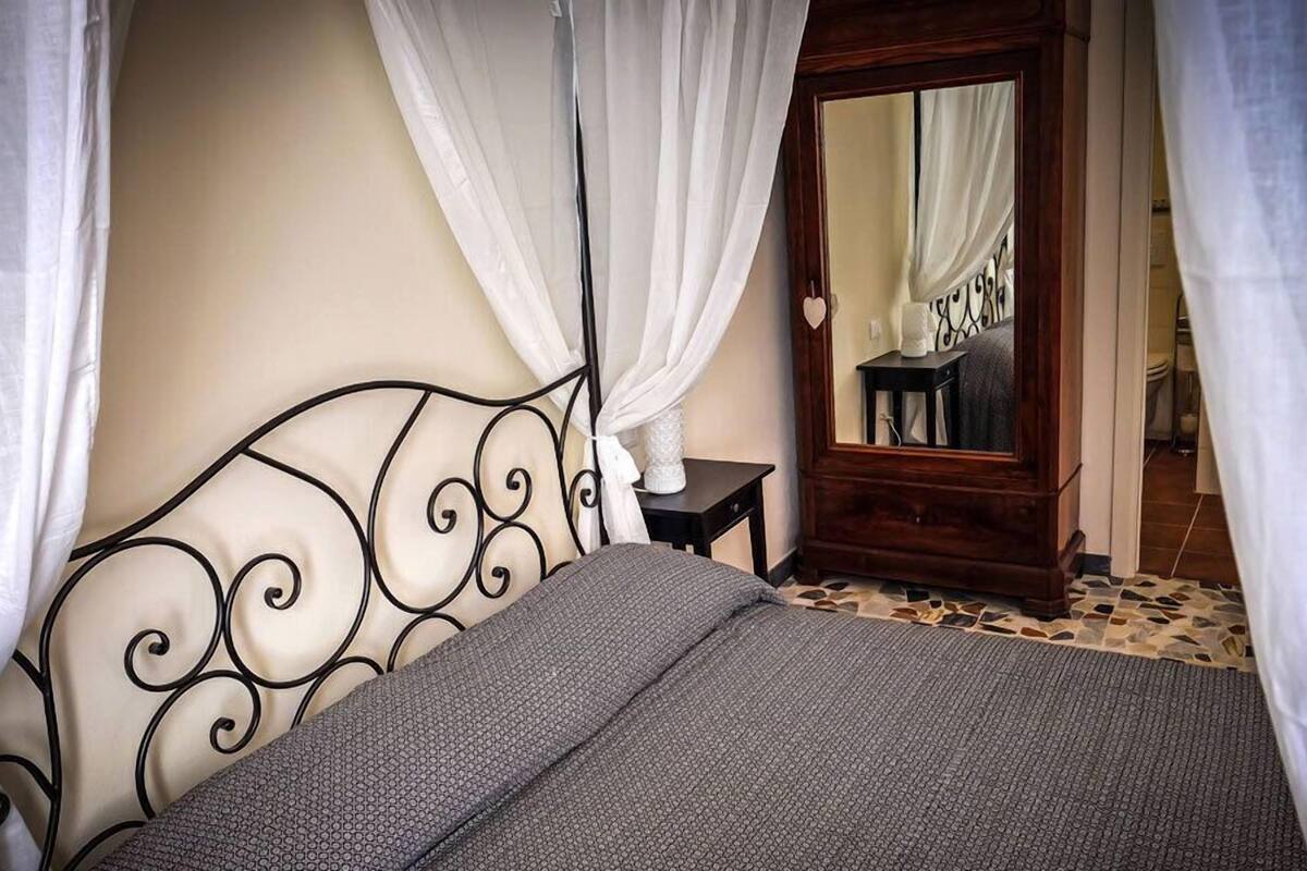 A bedroom with a bed, a nightstand, a mirror, and a door.