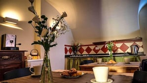 A dining area with a table set for two, a coffee machine, and a vase with flowers. - B&B U Campanin (Dolceacqua)