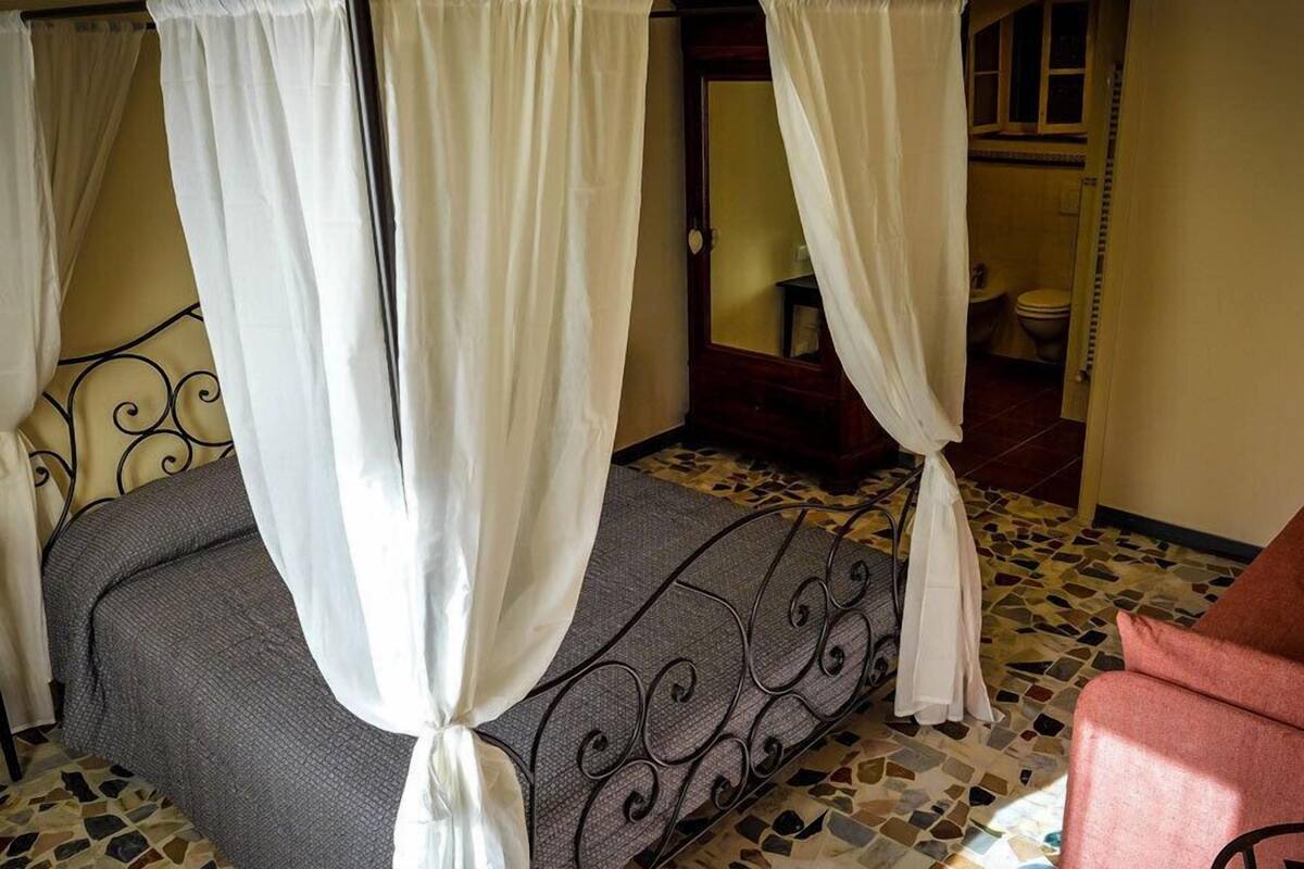 A room with a bed, a chair, and a bathroom visible through an open door.