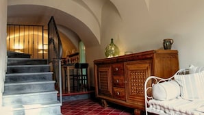 A staircase leading to a landing with a wooden cabinet and a bed with striped bedding. - B&B U Campanin (Dolceacqua)
