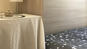 Et hotelværelse med et rundt bord, en lampe, en dekorativ skål og en seng med dynebetræk med stjerne-mønster.