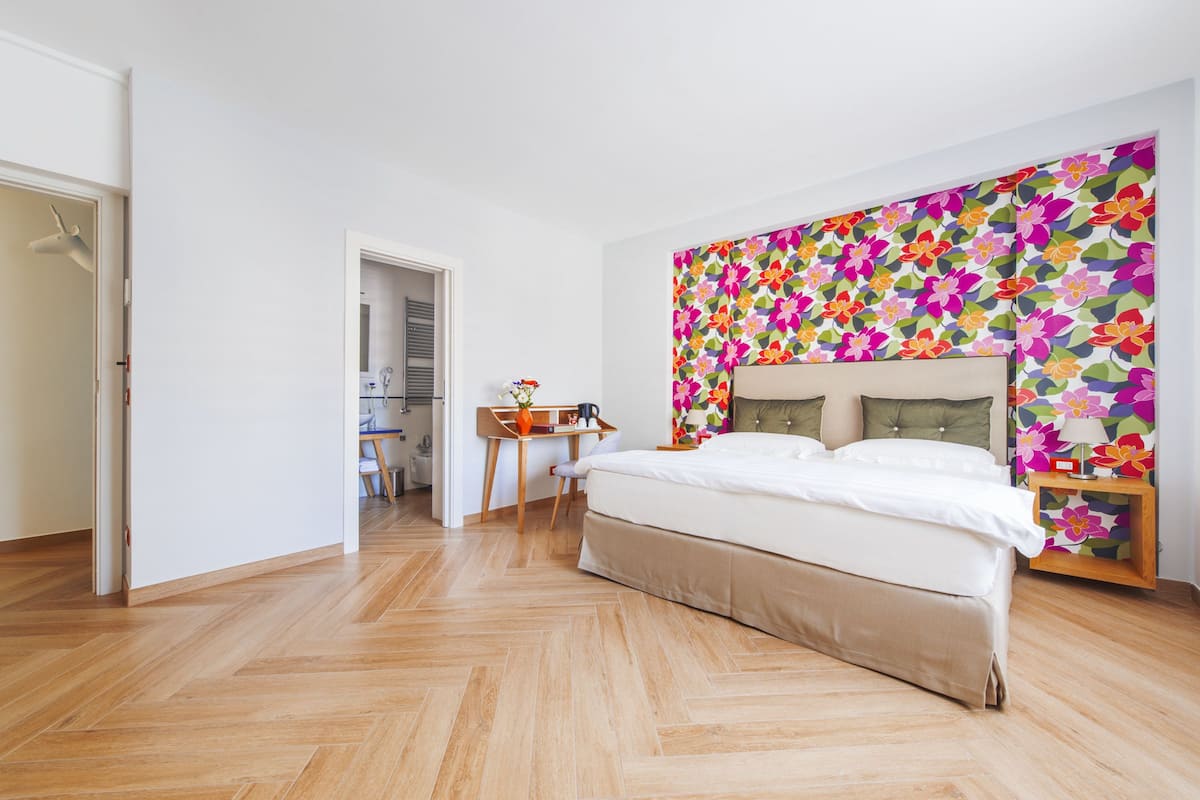 A bedroom with a large bed, a desk, and a chair.