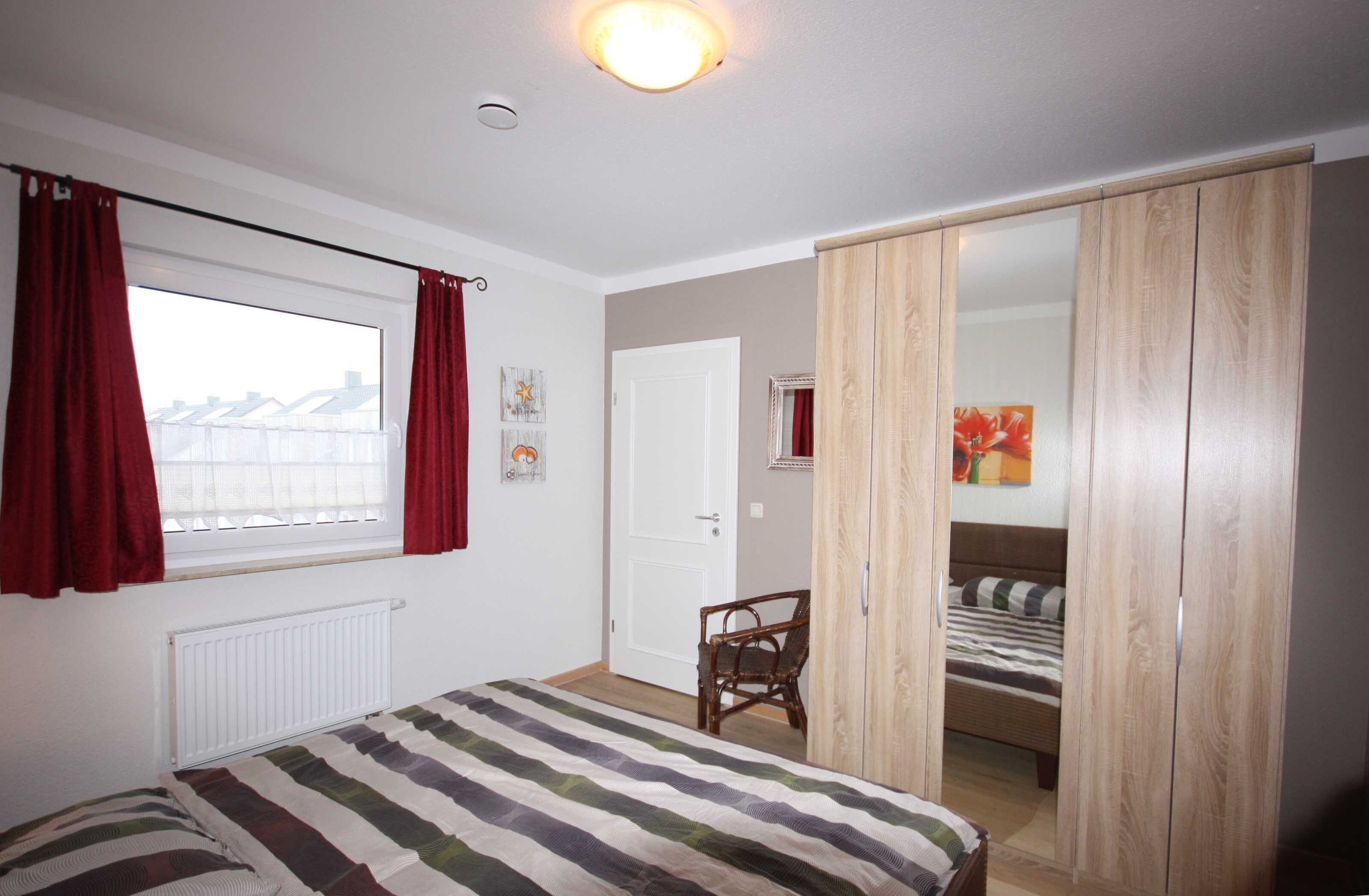 Une chambre à coucher avec un lit, une chaise, une armoire et une fenêtre avec des rideaux.