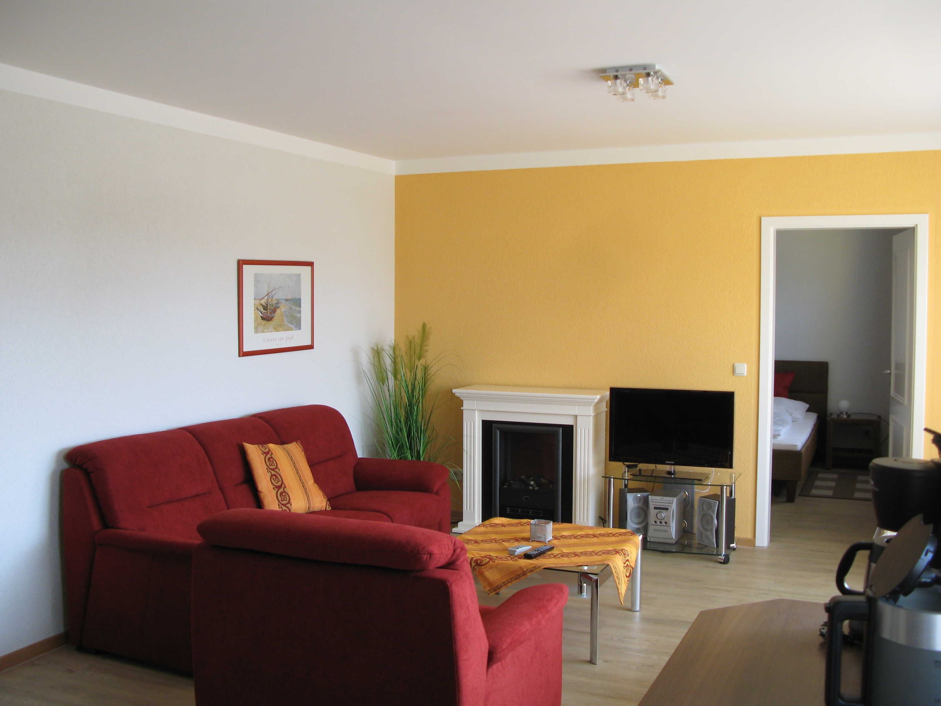 Una sala de estar con un sofá rojo, chimenea, televisor y cafetera.