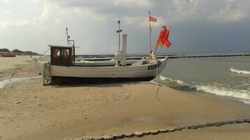Un bateau sur une plage de sable, avec une digue rocheuse en arrière-plan.