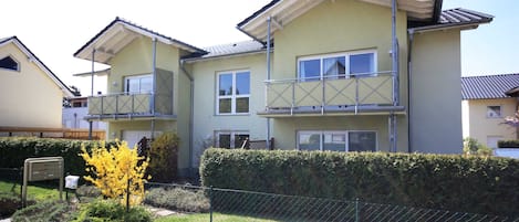 A residential building with multiple balconies, a gated entrance, and a well-maintained garden.
