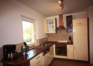 A compact kitchen with a coffee maker, a stove, and cabinets.