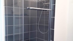 A glass-enclosed shower stall with a metal handle and a showerhead. - Pretty Penty in the heart of Trégor (Pommerit-Jaudy)