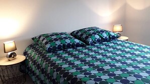 A bedroom with a bed, two bedside tables, and a wall socket. - Pretty Penty in the heart of Trégor (Pommerit-Jaudy)