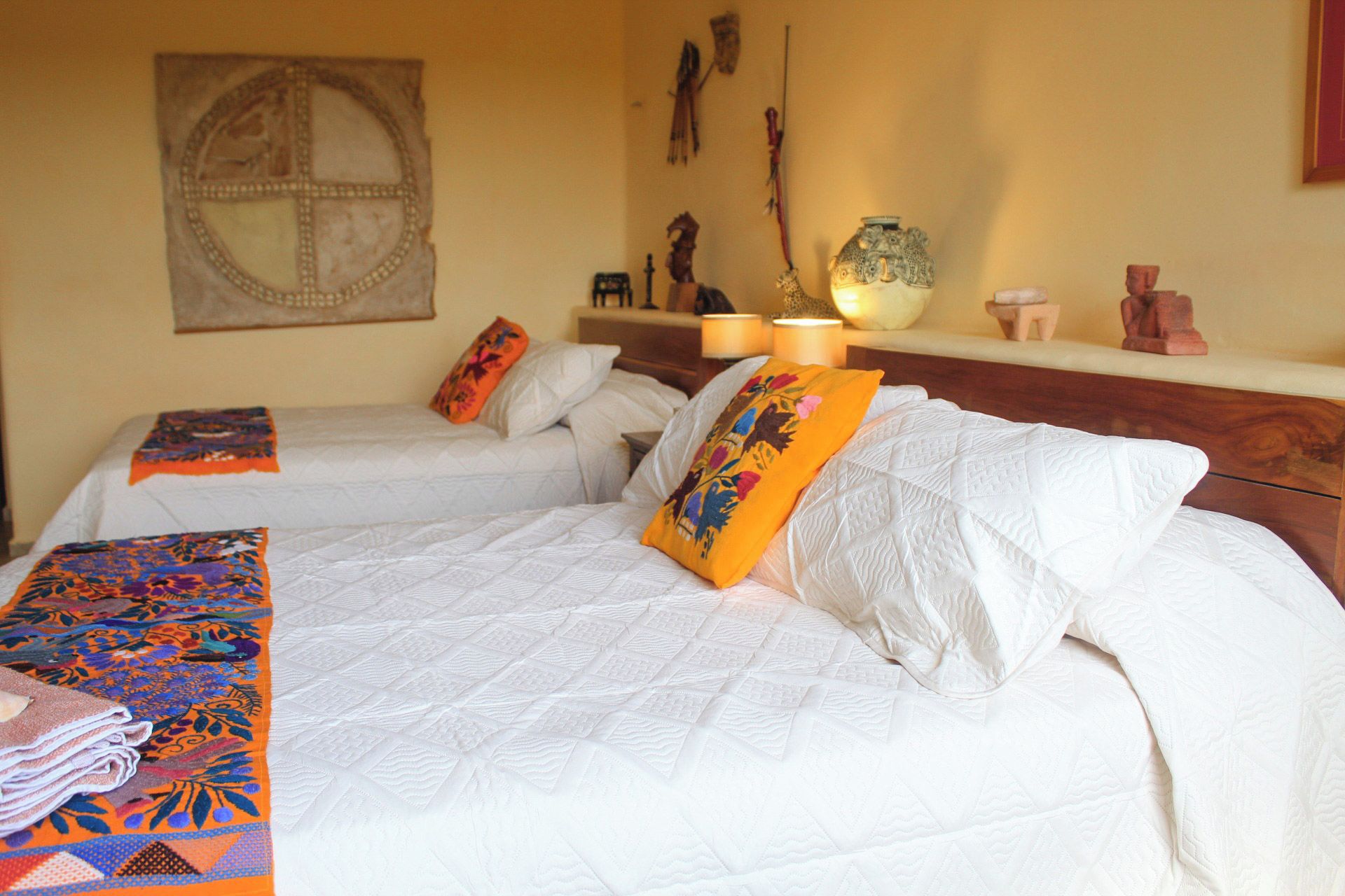 Une chambre d’hôtel avec deux lits, un élément décoratif mural et une table de chevet avec une lampe.
