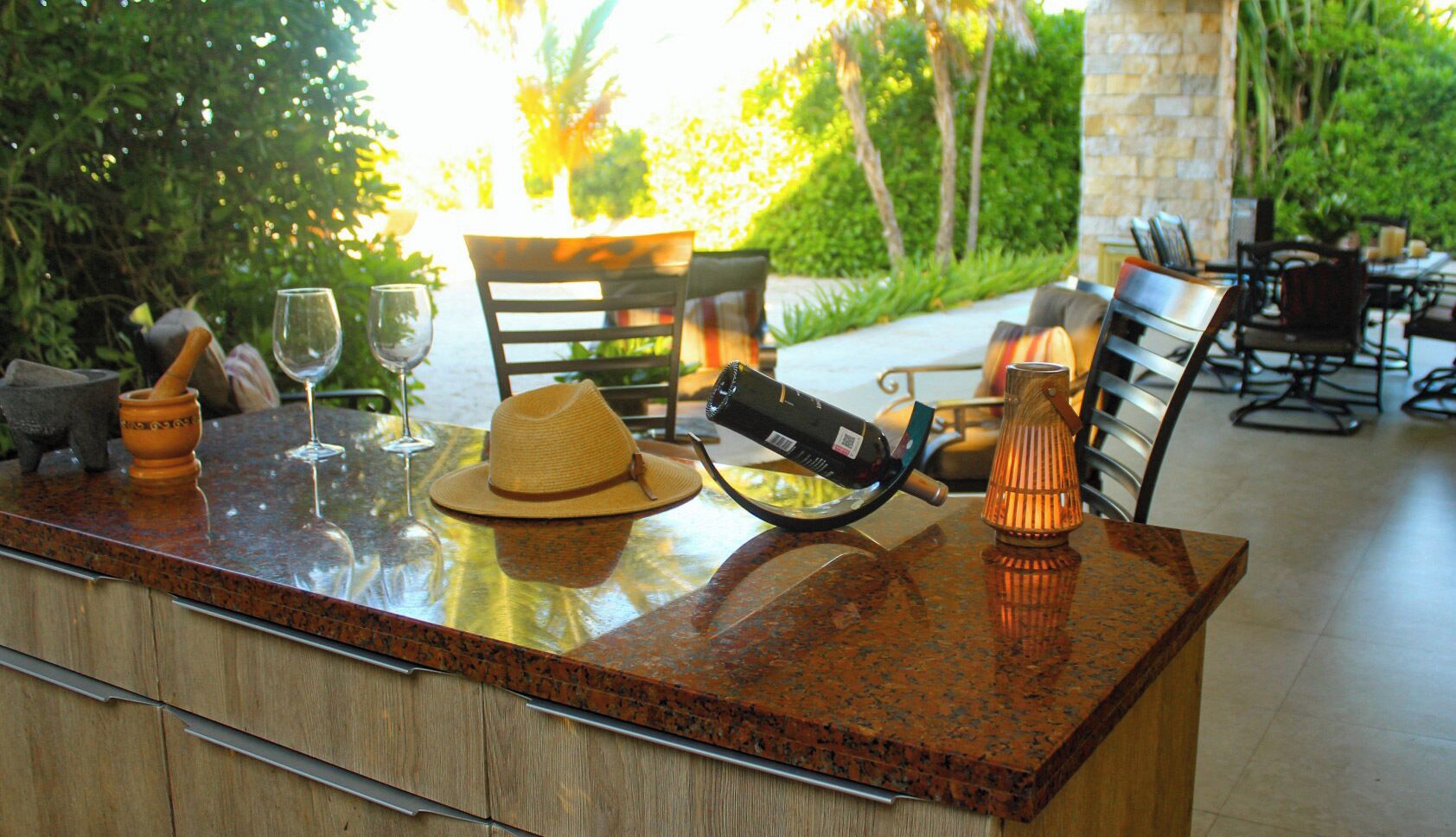 A bar area with a granite countertop, a hat, a wine glass, a bottle, and a candle.