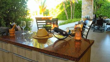 A bar area with a granite countertop, a hat, a wine glass, a bottle, and a candle.