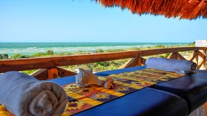 Una tumbona con vistas al océano, una toalla enrollada y una concha decorativa.