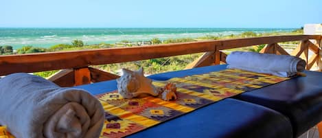 A sun lounger with a view of the ocean, a rolled towel, and a decorative shell.