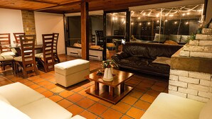 Un salon avec une table en verre, des chaises en bois, un canapé et une cheminée.