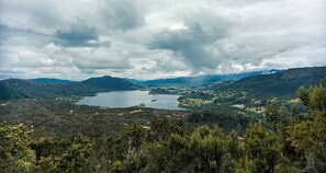 A lake surrounded by forested hills and a cloudy sky. - Hostal San Rafael La Calera (La Calera)