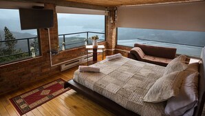 Une chambre avec un grand lit, une vue sur la mer et un balcon doté d’une balustrade.