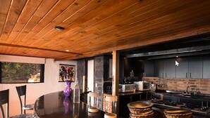 Une cuisine moderne avec des meubles de couleur sombre, un plafond en bois et un coin repas comprenant une table ronde et des chaises.