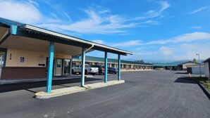 A motel with a covered parking area, a visible handicap parking sign, and a building with a green roof. - Travel Inn (Fortuna)