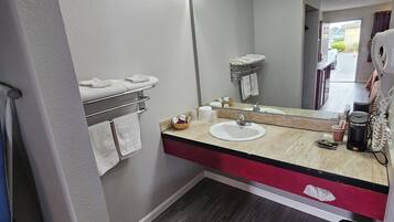 A modern bathroom with a large mirror, a sink, and a towel rack.