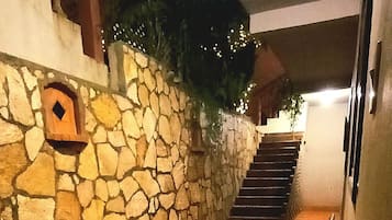 Un muro de piedra con un banco de madera y una escalera que lleva a un nivel superior.