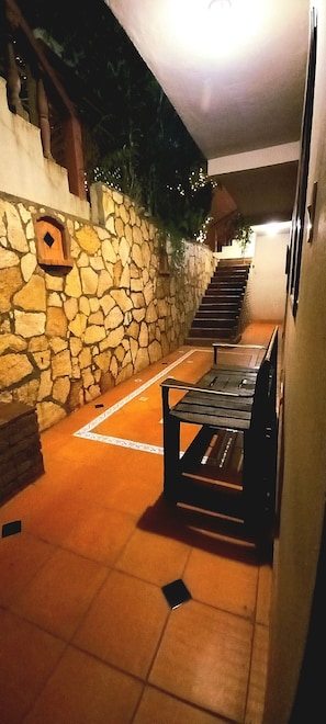 A stone wall with a wooden bench and a staircase leading to an upper level. - Hotel Rosalila (Copan Ruinas)