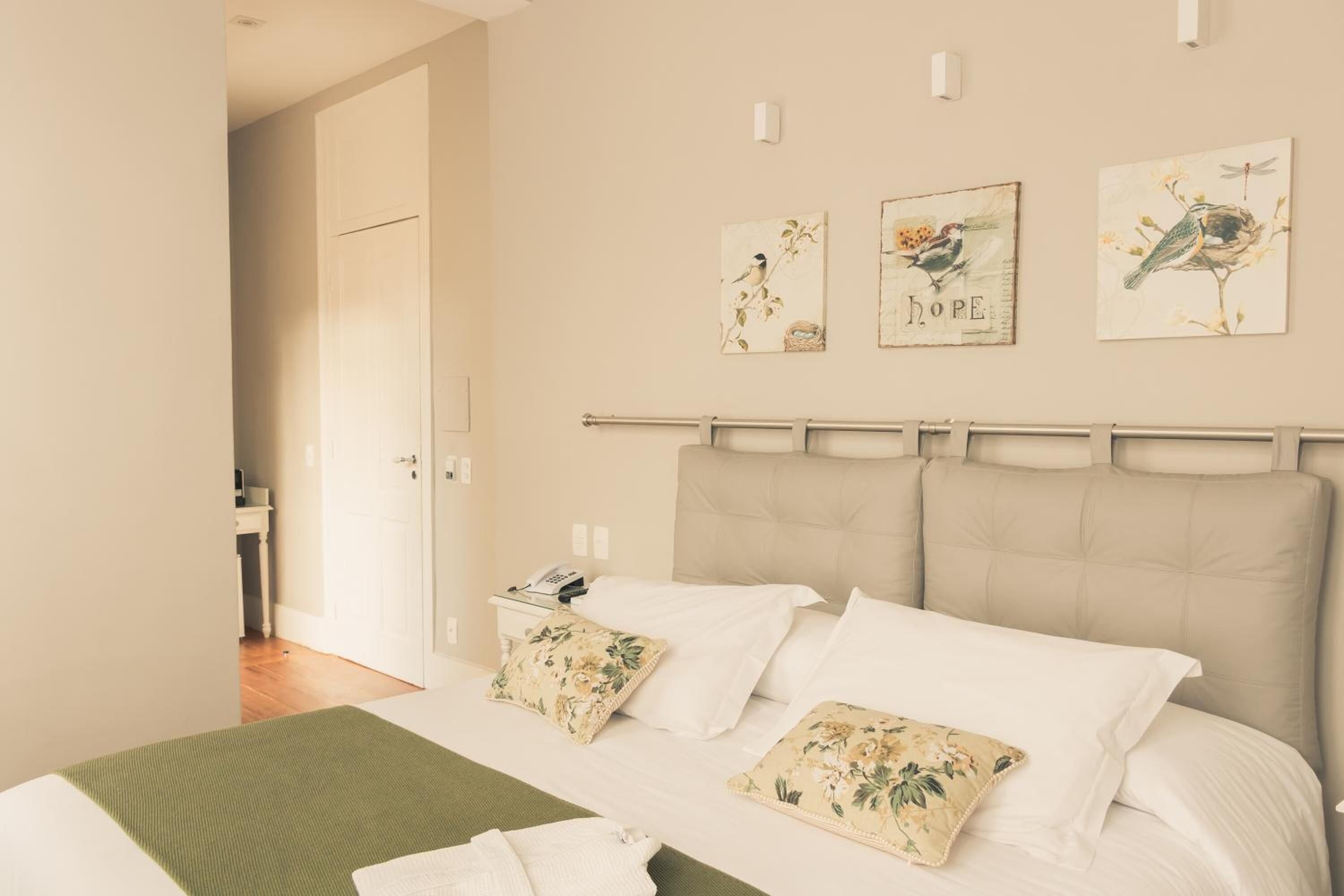 A bedroom with a bed, pillows, a bedside table, and a wall with artwork.