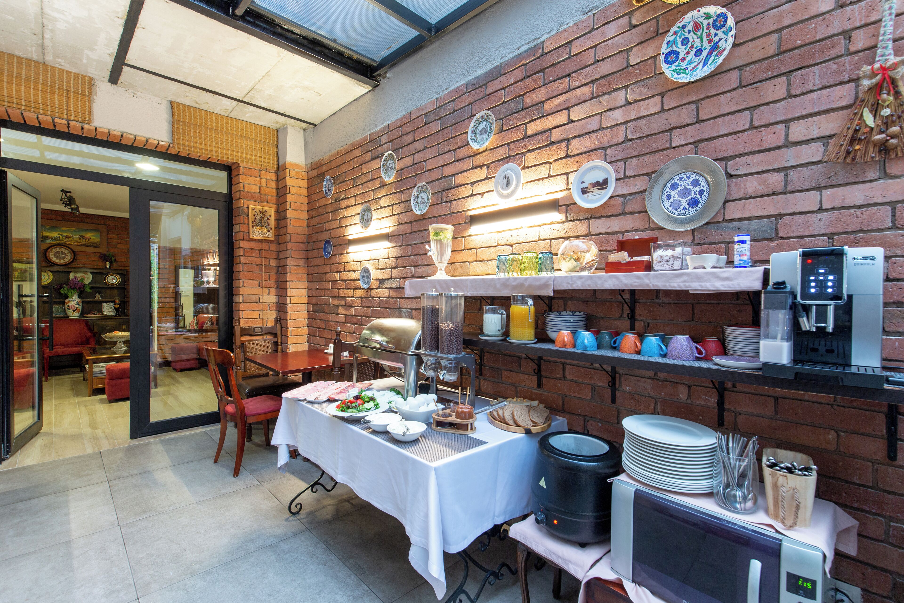 A breakfast buffet with a variety of dishes, a coffee machine, and a brick wall with decorative plates.