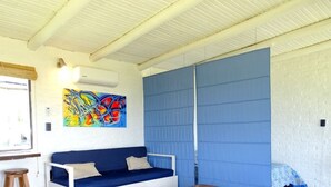 Ein Zimmer mit einem blauen Sofa, einem farbenfrohen abstrakten Gemälde und einer großen, blauen Schiebetür.