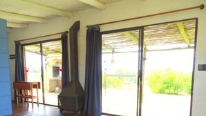 Ein Zimmer mit einer Schiebetür zum Balkon, einem Holzstuhl und einem Grill davor.