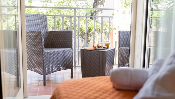 Un balcon avec des fauteuils en osier et une petite table sur laquelle sont posées une boisson et des en-cas.
