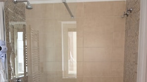 Une salle de bain avec une douche à l’italienne, un lavabo blanc et des carreaux décorés.