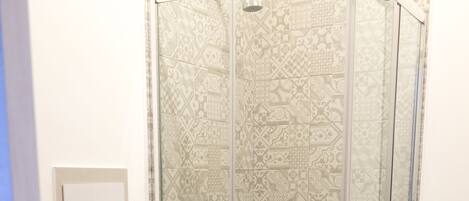 Un baño con ducha acristalada, inodoro y bidé.
