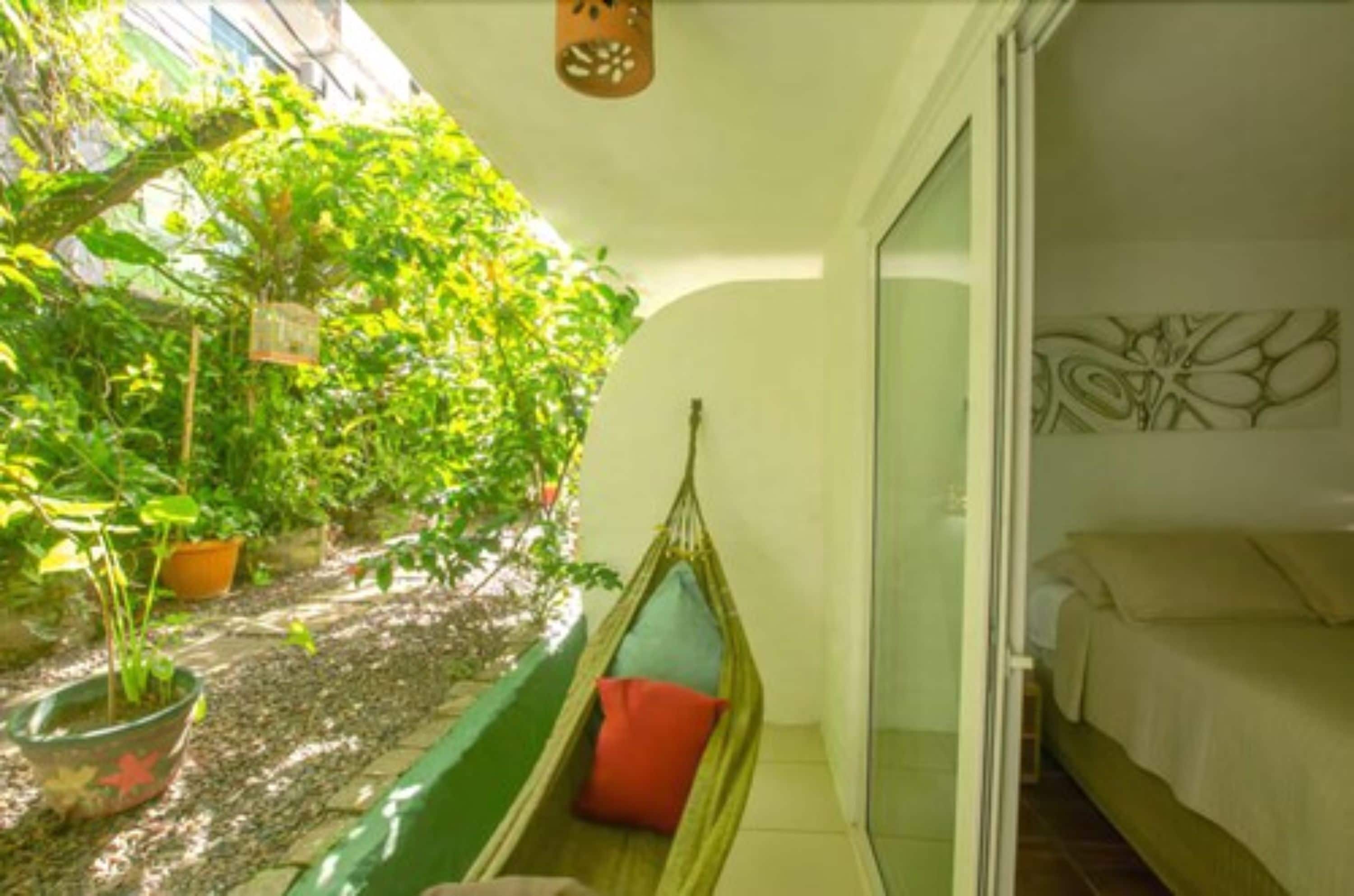 A room with a bed, a hammock, and a small garden area with potted plants.