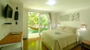 A bedroom with a bed, a television, a desk, and a view of the outdoors. - Pousada Borboleta (Cairu)