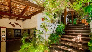 A reception area with a wooden staircase, potted plants, and a wall with fish decorations. - Pousada Borboleta (Cairu)
