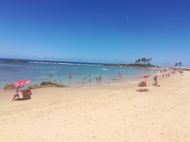 Perto da praia, areia branca, espreguiçadeiras, guarda-sóis 