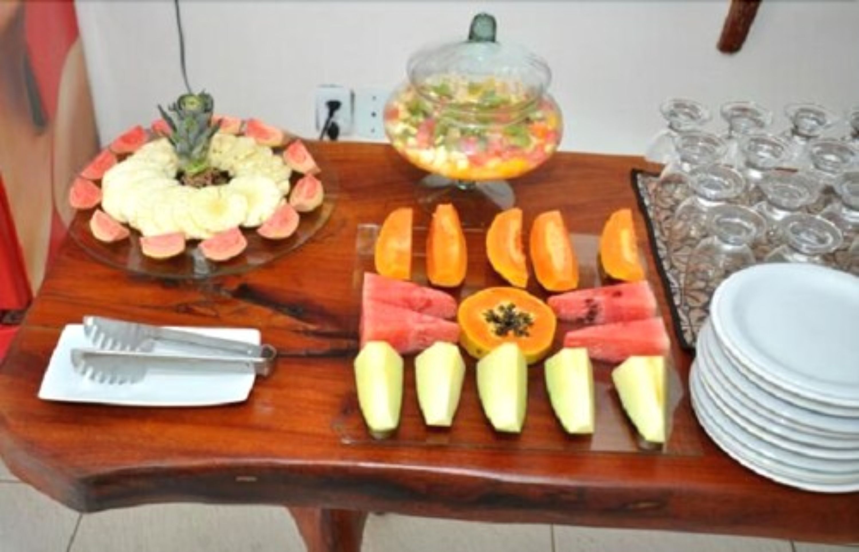 Una mesa de madera con diversas frutas y un bol de ensalada de frutas.
